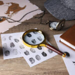 Magnifying glass with fingerprints, map and hat