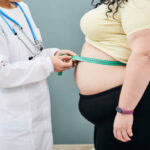 obesity-unhealthy-weight-nutritionist-inspecting-a-womans-waist-using-a-meter-tape-to (1)